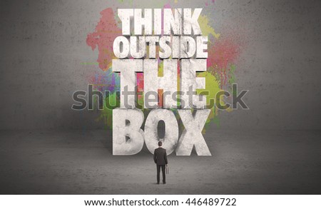 Colorful wall with illustrated quote saying think outside the box for a small businessman standing in grey urban space concept