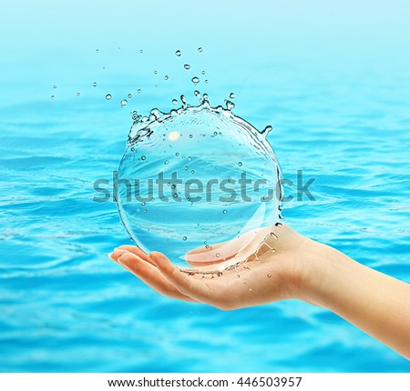 Female hand holding water ball splash on blue water background