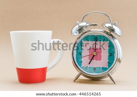 Alarm clock is showing time for 7 AM and a cup of coffee at site for morning coffee