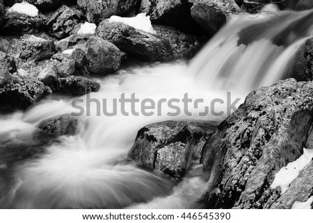 close-up of rocks in river brook in satin soft waterfall in black and white