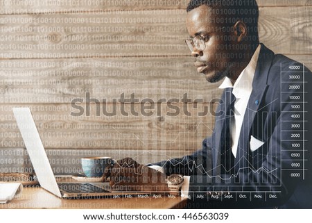 Double exposure. Visual effects. Dark skinned market expert sitting at a cafe, using his laptop, doing analyzes of current market conditions, dressed in dark blue suit, looking concentrated and busy