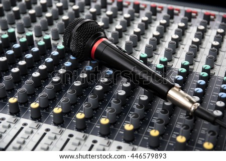 microphone on a professional sound mixing console with adjusting knobs, music device for audio signal, selected focus, narrow depth of field