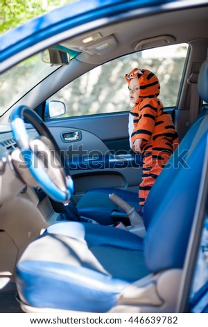 little boy in tiger costume is in the car