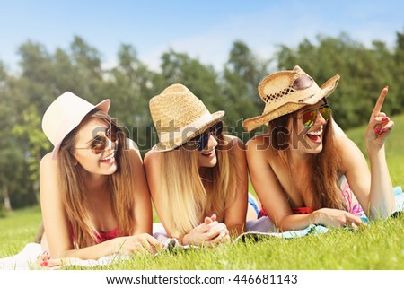 Picture presenting a group of women in bikin showing something outdoors