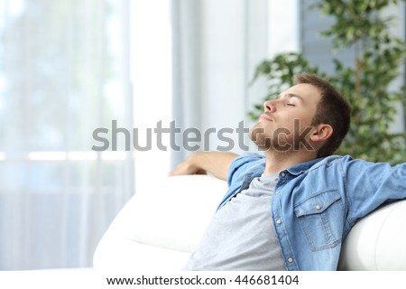 Portrait of a casual tired man resting sitting on a couch at home Royalty-Free Stock Photo #446681404