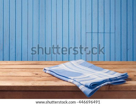 Empty wooden table with tablecloth over blue wood wall background. Background for food product display montage.
