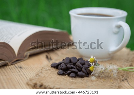 Cup of black coffee,coffee beans and a book on wooden background.