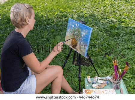 Female artist paints in oil on the open air.