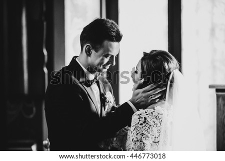 A black and white picture of a groom smiling to the bride while holding her face in his palms