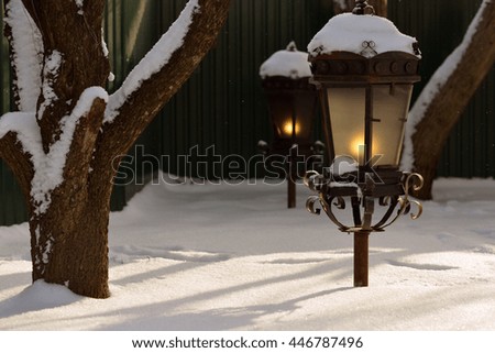 Winter. Evening. Lantern light and cast reflections on the snow.