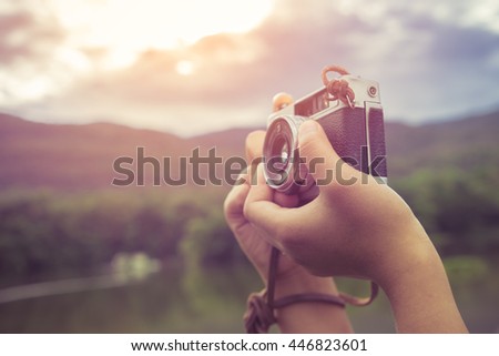 Close-up shot of woman hand holding retro camera - vintage filter color effect style