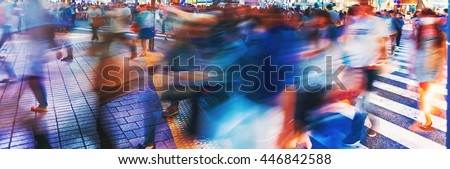 Motion blurred crowds converge at Shibuya Crossing, one of the busiest crosswalks in the world. Tokyo, Japan