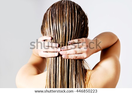 Woman applying hair conditioner. Isolated on white. Royalty-Free Stock Photo #446850223