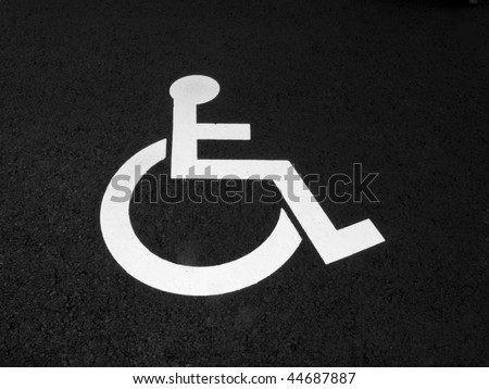 White handicap sign on black asphalt.
