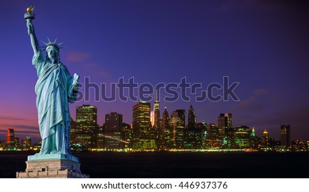 Manhattan skyline at night with blue sky and illuminated buildings and Statue of Liberty.