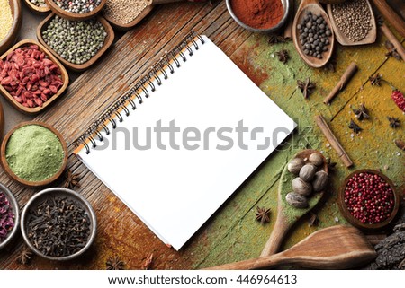 Open recipe book with colorful spices on wooden background, abstract compositions