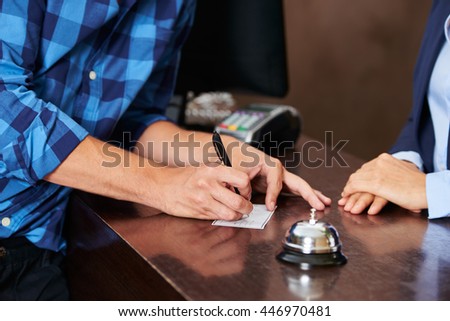 Guest at hotel reception paying with check during check-in
