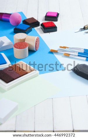 stamp ink pad, lino cutter , papers and rubbers on white wood table