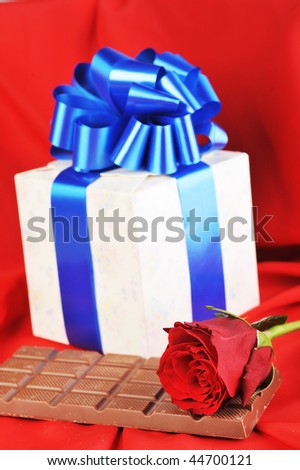 beautiful red rose, gift and chocolate  on red close up