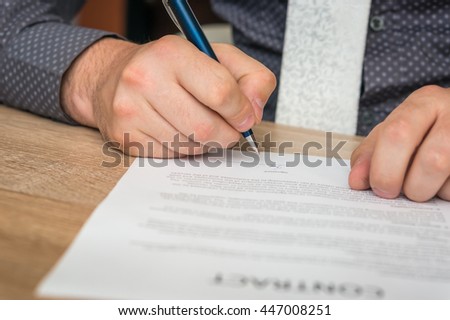 Businessman is signing a contract to conclude a deal - business concept