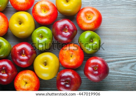 Ripe red green and yellow apples on wooden board, background