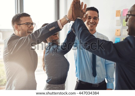 Happy successful multiracial business team giving a high fives gesture as they laugh and cheer their success Royalty-Free Stock Photo #447034384
