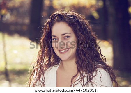 Portrait of smiling young caucasian woman in a park. Toned photo