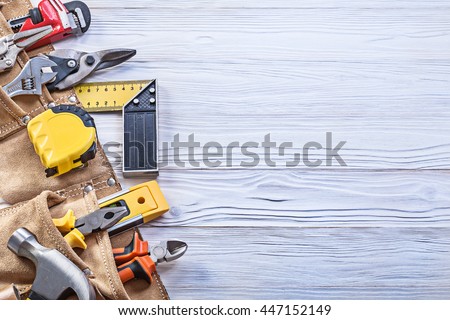 Construction tooling in leather toolbelt on wooden board copy space maintenance concept. Royalty-Free Stock Photo #447152149