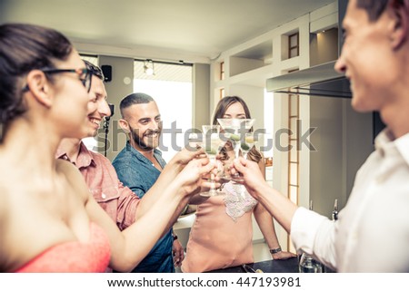 Group of friends having party at home and toasting cocktail glasses