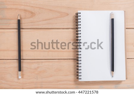 Blank Notebook with black pencil on wood table for background

