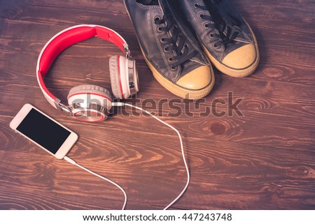 Travel Concept with blabk sneakers and smartphone with red  headphones on wooden floor background.