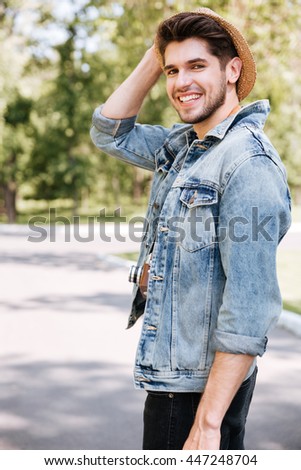 Close-up portrait of a handsome hipster guy holding camera wearing hat outdoors in the park