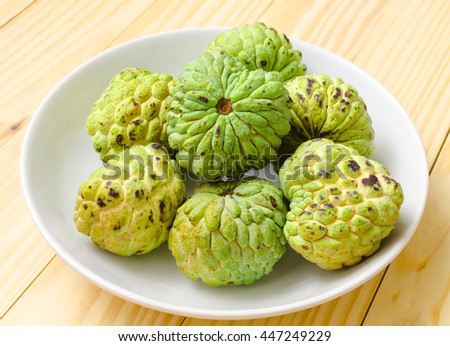 custard apple fruit on white plate with wood background