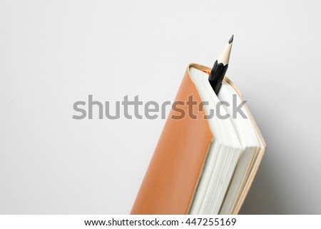 Pencil insert between leather diary on white desk Royalty-Free Stock Photo #447255169