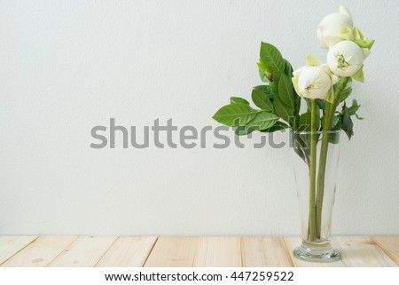 Flowers or lotus flowers in the vase on wooden floor with concrete wall for background.