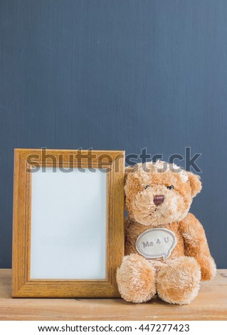 Photo frame with single brown teddy bear at chest has a message " Me 4 U" sitting on old wooden table, black background. Emphasizing copy space for write text.