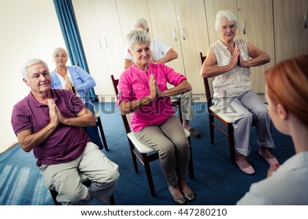 Group of seniors doing exercises with nurse in the retirement house