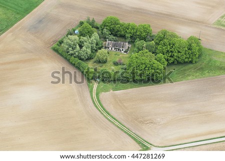 Old farm surrounded by trees with height of bird's flight in France.