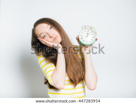 yawning beautiful young woman with alarm clock, isolated on a gray background