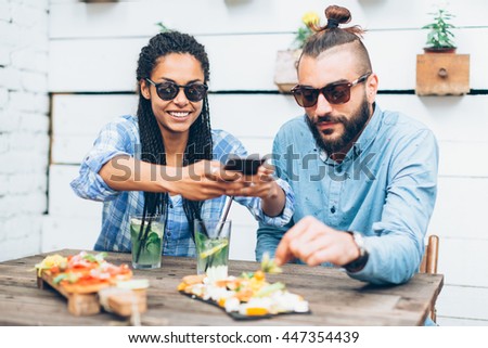 Young couple sitting in the restaurant and taking pictures of the food with mobile phone 

