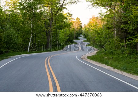 Long winding road going thru a country side. Royalty-Free Stock Photo #447370063