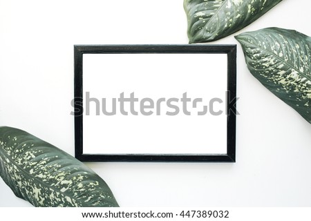 Empty photo frame and green leaves isolated on white. flat lay, top view