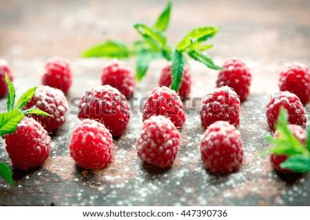 Ripe sweet raspberries with mint on wooden background