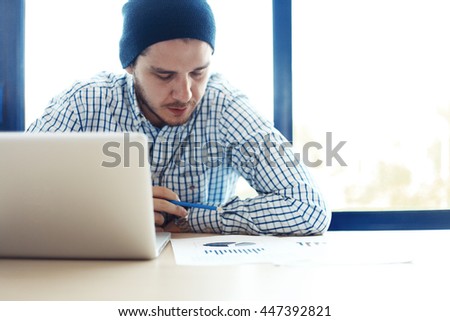 Business man working at office with laptop and documents on his desk. Analyze plans, papers, hands keyboard. Blurred background, film effect