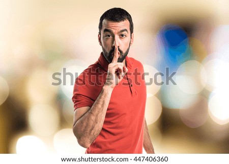 Handsome man making silence gesture on unfocused background