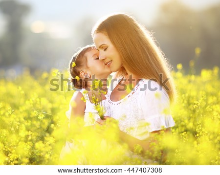 Happy family on a summer meadow. little girl child daughter hugging and kissing mother