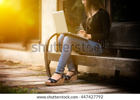 Young woman using credit card and choose product shopping by laptop, beautiful fashion girl using laptop to buy a product concept in vintage tone and sunlight effect.