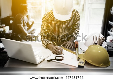 Architect engineer is working very hard to drawing a blueprint to be presented to head of monitoring, working desk of engineer is messy, front view photography with vintage picture style.