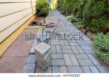 Stone Pavers and tiles for side yard patio hardscape with garden landscaping tools rubber mallet sand gravel tamper level rake Royalty-Free Stock Photo #447440287