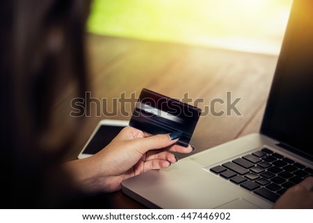 Young asian woman using black color of credit card to buy online product, beautiful girl using laptop for shopping online and payment by credit card easy way, vintage tone picture style photography.